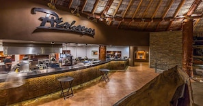 A restaurant interior with a bar area, stone accents, and a thatched roof.
