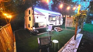 A caravan with a kitchen area, a dining table, and a chair. - Come Glamping in this luxurious 2022 RV in DT FT MYERS, Very Private Space! (Fort Myers)