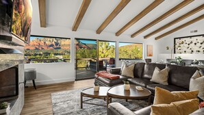 Un salon moderne doté d’un grand canapé d’angle, d’une cheminée et offrant une vue imprenable grâce à de grandes fenêtres.