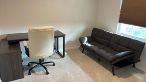 Une pièce comprenant un bureau, un fauteuil de bureau et un canapé.