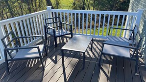Une terrasse avec une balustrade blanche, une table et deux chaises.