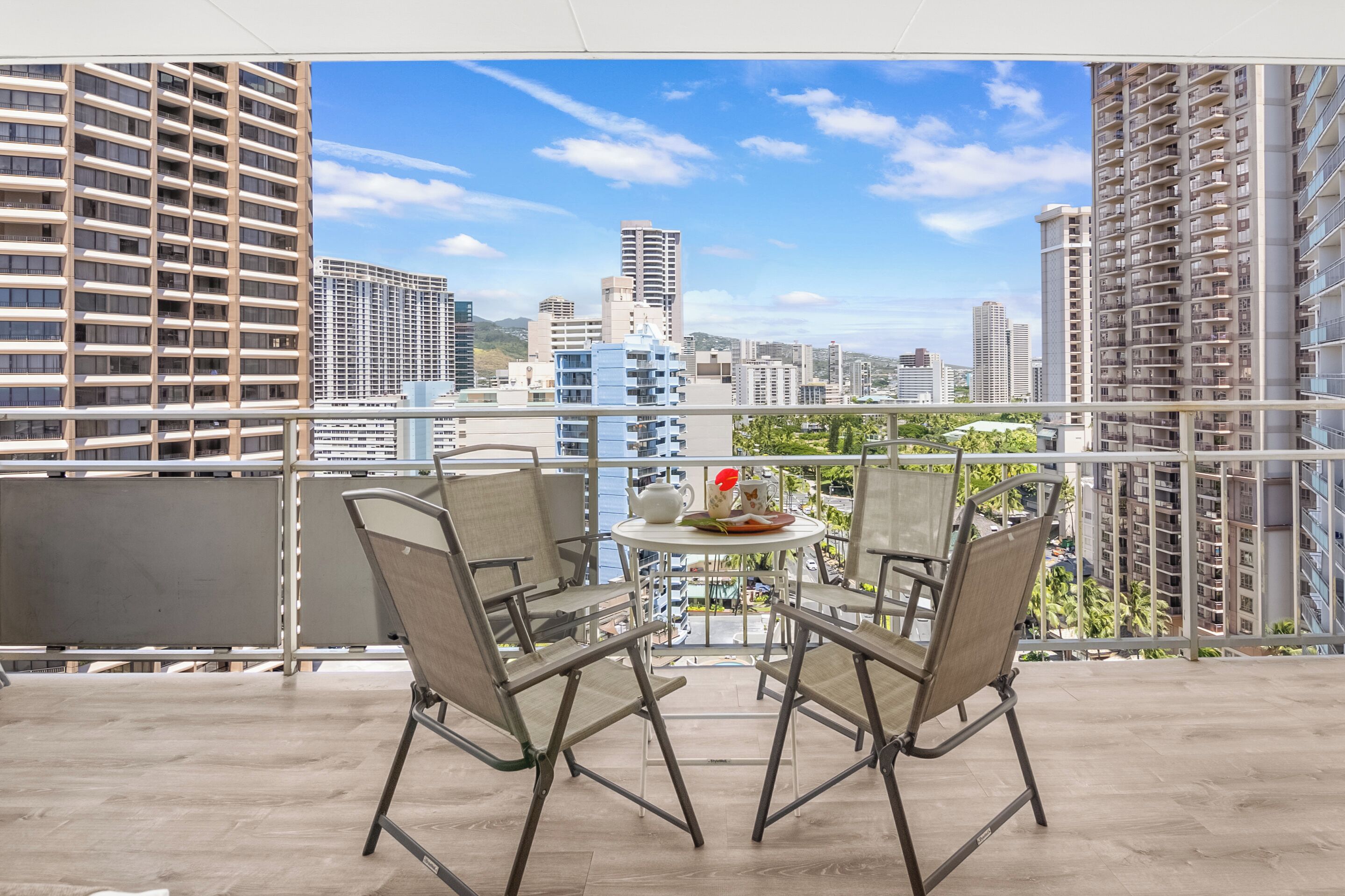 En balkon med to stole og et lille bord, der giver udsigt over en by med høje bygninger.