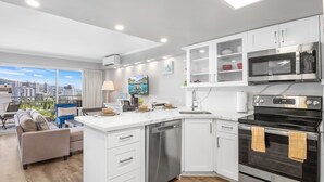 A modern kitchen with white cabinetry, a built-in dishwasher, a stainless steel microwave, and an oven. - Ilikai Hotel Condo at Waikiki No Parking (Honolulu)