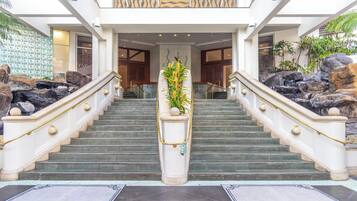 A grand staircase with a central planter, flanked by large rocks and leading to a building entrance.