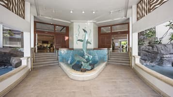 A spacious lobby with a central fountain, a staircase, and a view of a restaurant.