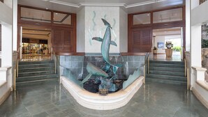 A lobby with a central aquarium featuring a dolphin sculpture. - Ilikai Hotel Condo at Waikiki No Parking (Honolulu)