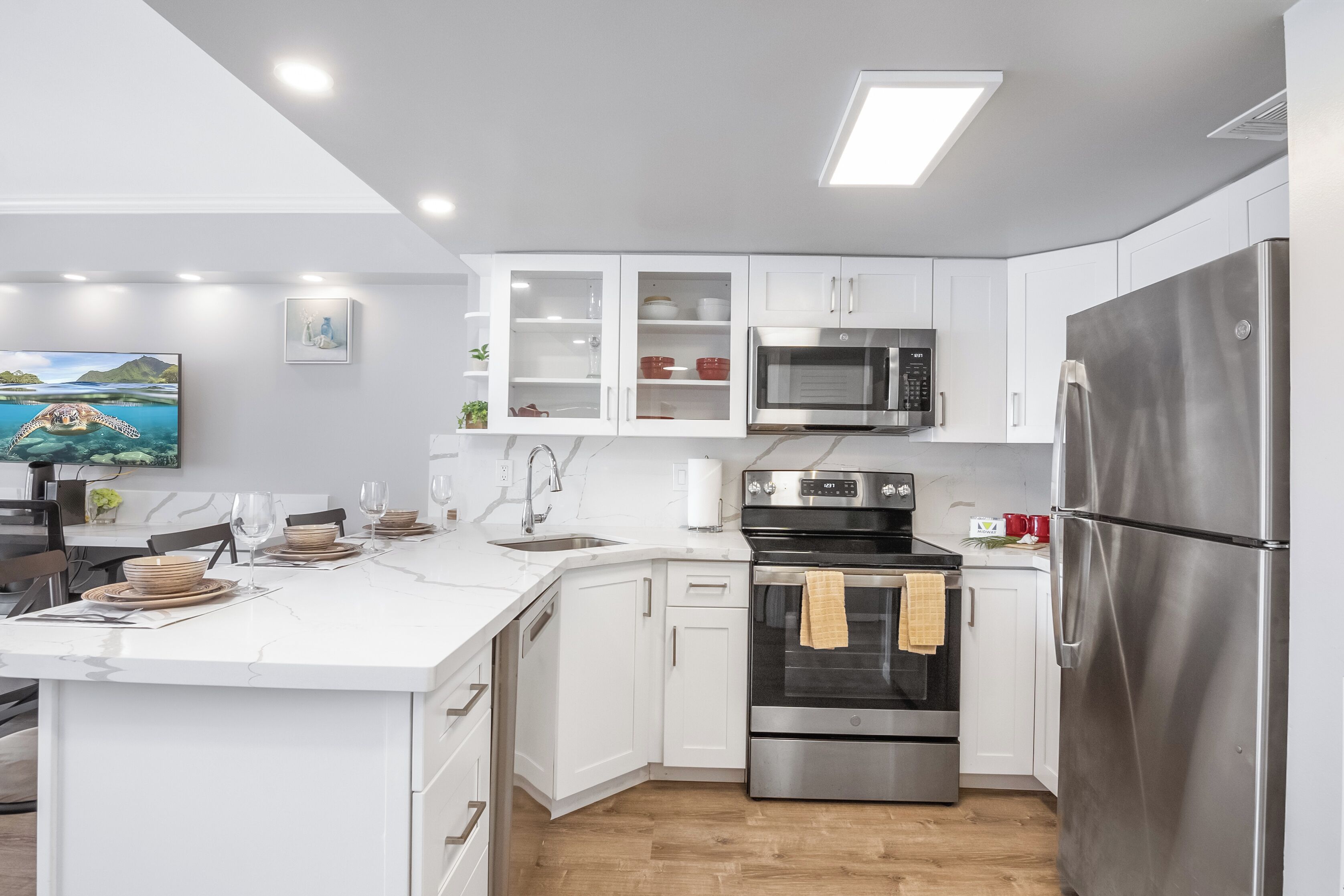 A modern kitchen with white cabinetry, stainless steel appliances, and a large island with seating.