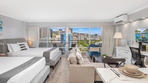 A hotel room with two beds, a sofa, a dining table, and a view of the city. - Ilikai Hotel Condo at Waikiki No Parking (Honolulu)