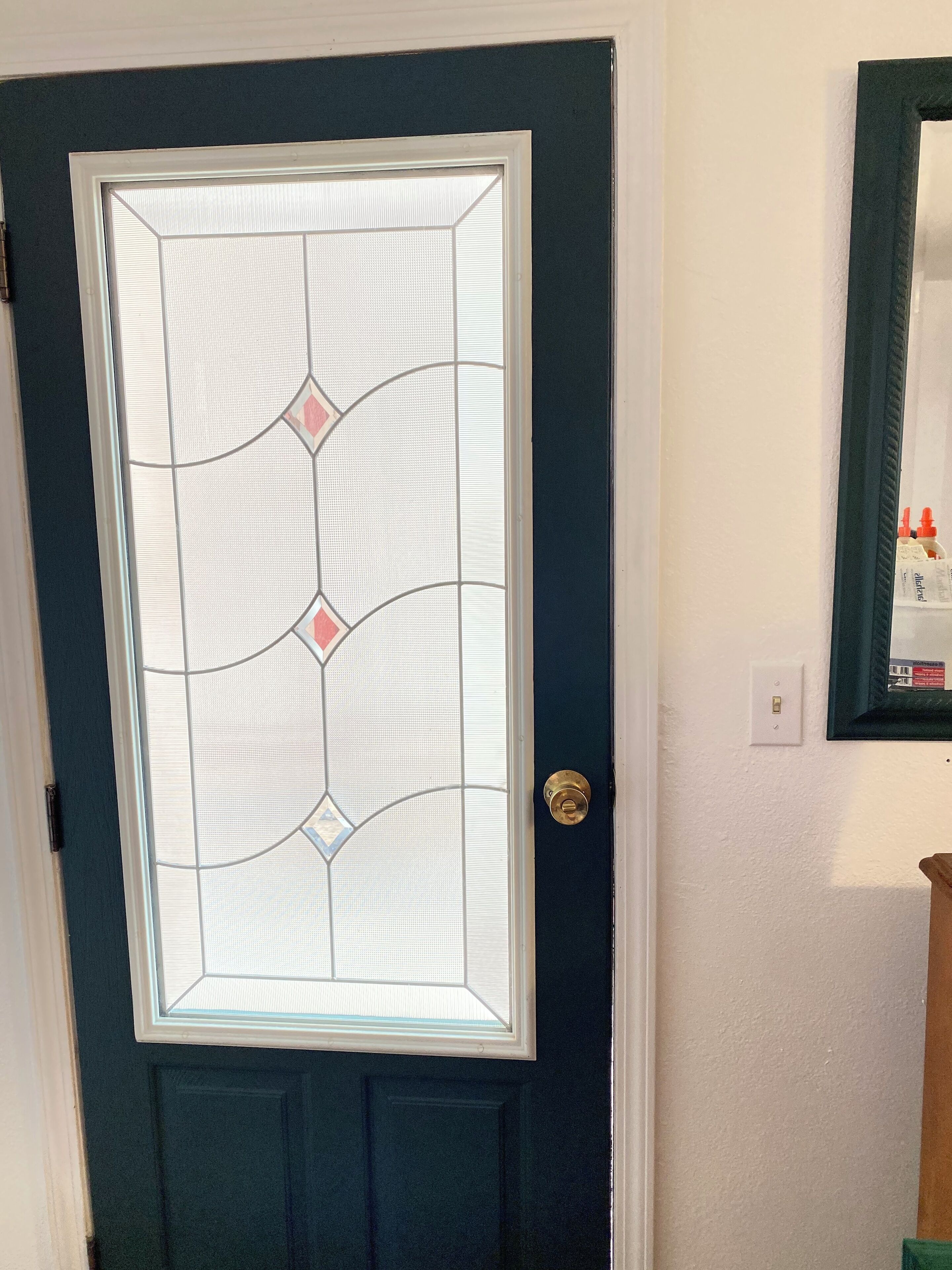 A dark blue door with a decorative glass panel featuring geometric patterns.