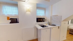 A compact kitchenette with a microwave, toaster, and sink. - Studio Castelnau (Strasbourg)