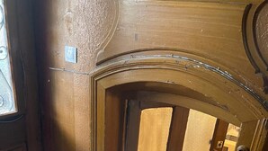 A wooden door with a decorative arch, a tiled floor, and a visible window to the left. - Studio Castelnau (Strasbourg)