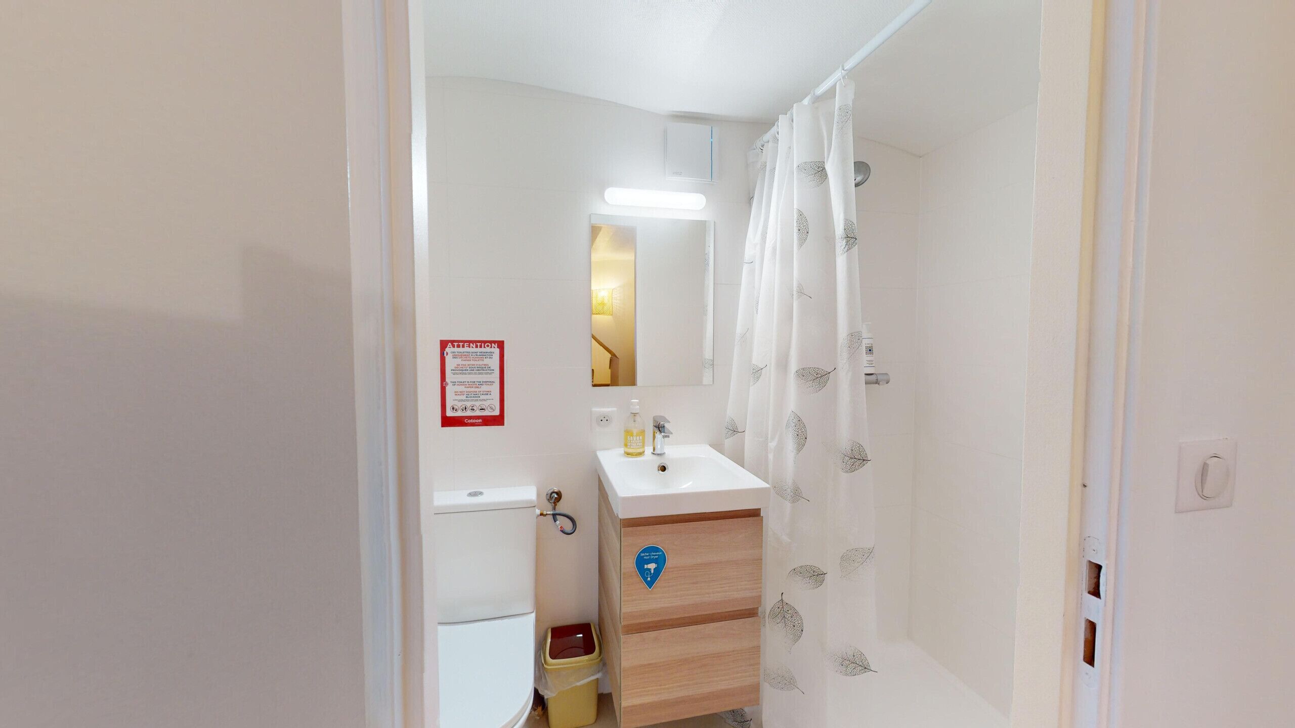 A bathroom with a sink, mirror, and shower curtain.