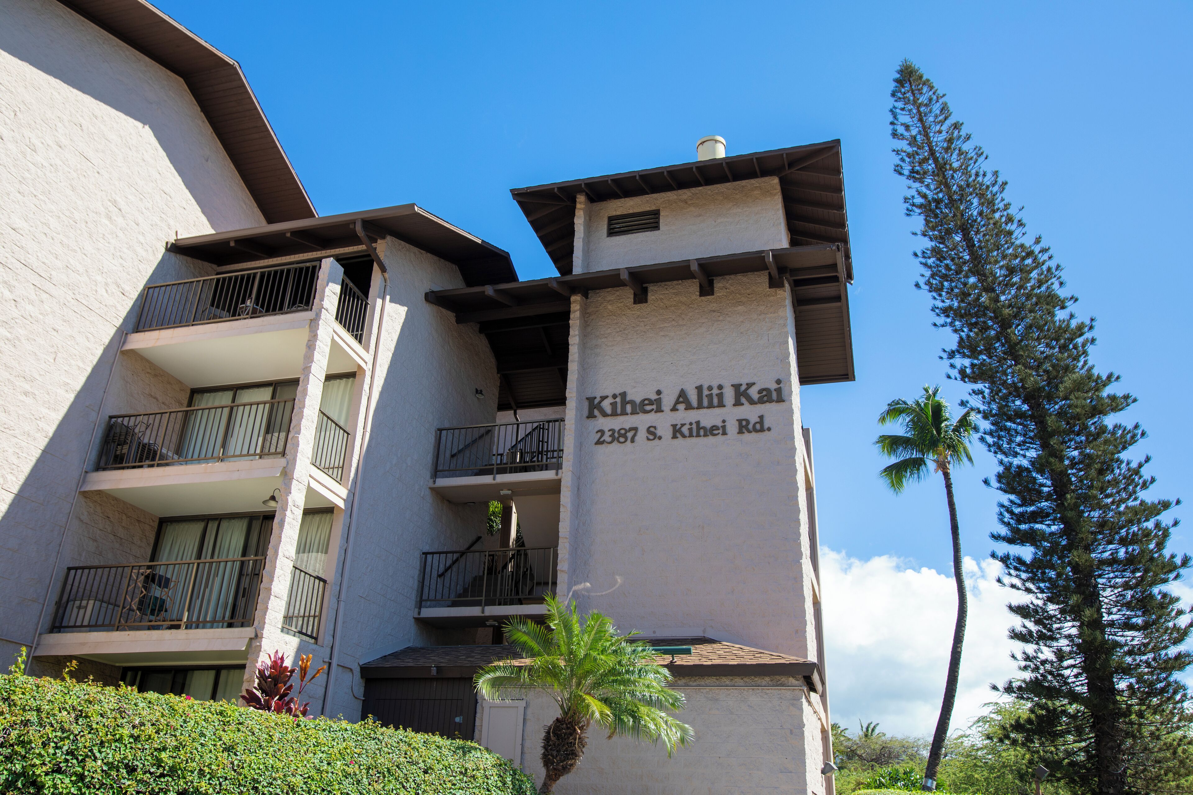 Un immeuble à plusieurs étages doté de balcons et d’une enseigne indiquant « Kihei Alii Kai 2387 S. Kihei Rd. »