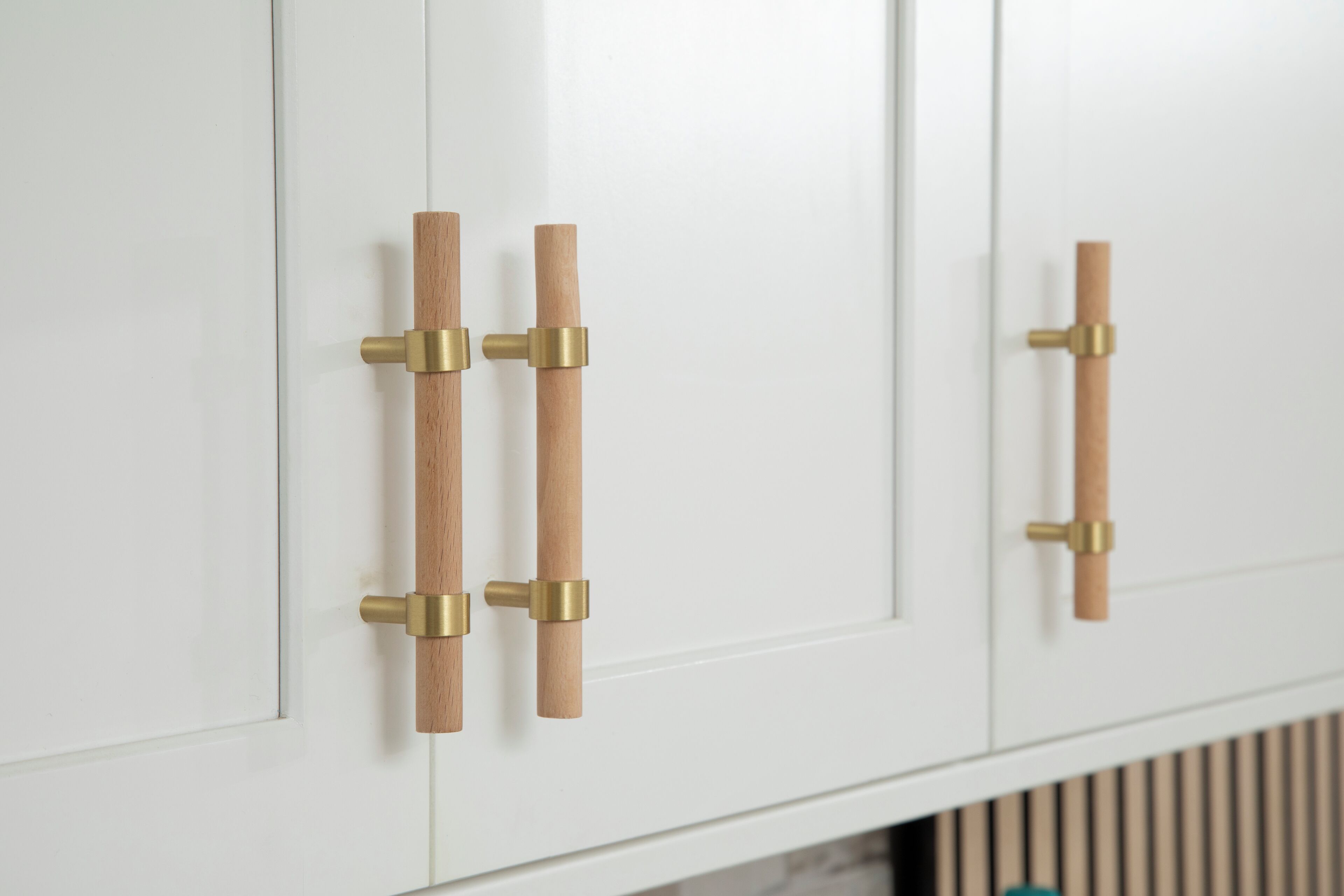A white cabinet with two wooden handles and brass fixtures.