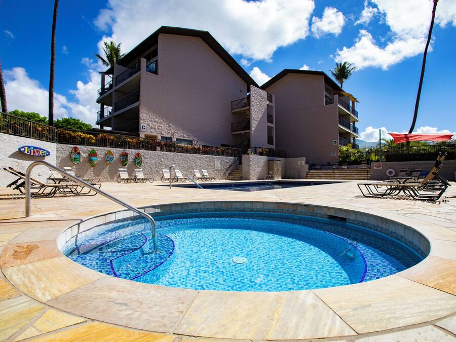 A swimming pool with a tiled deck, a lifeguard stand, and lounge chairs.