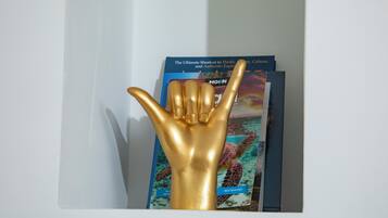 Una escultura dorada de una mano frente a una estantería con libros de viajes.