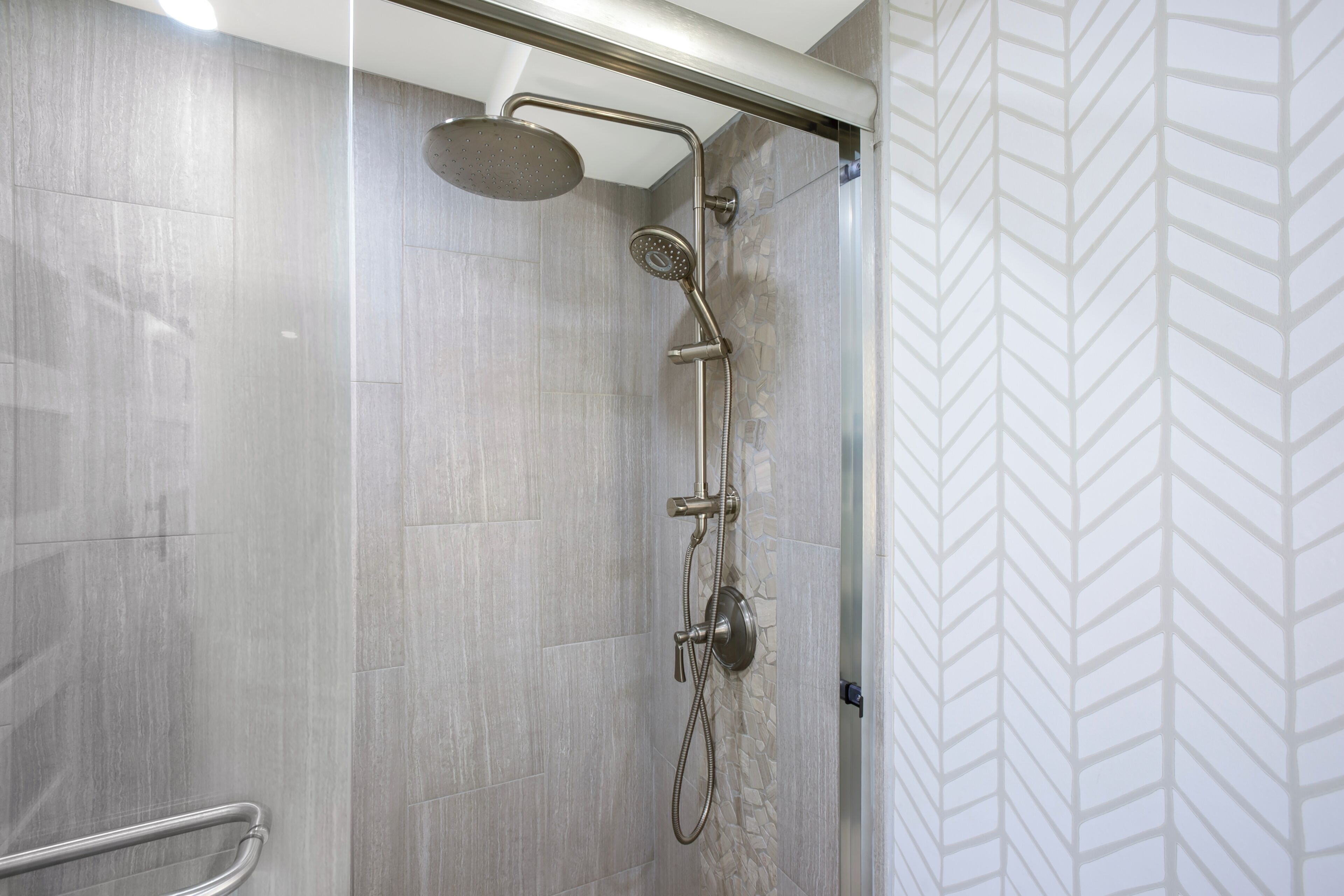 A shower with a handheld showerhead and a wall-mounted faucet.