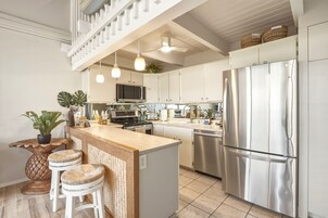 Cozinha moderna com ilha central, eletrodomésticos de aço inoxidável e luminária pendente.