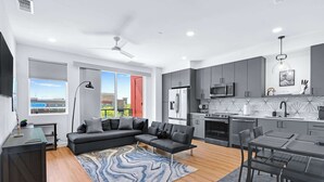 A modern kitchen with grey cabinets, a black dining table, and a large window. - Pacific Island Inspired Stay | Amazing Location (New Braunfels)