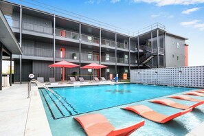 A modern building with a swimming pool, multiple balconies, and outdoor seating areas.