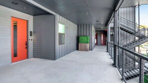 A modern corridor with a red door, grey walls, and a staircase on the right. - Pacific Island Inspired Stay | Amazing Location (New Braunfels)
