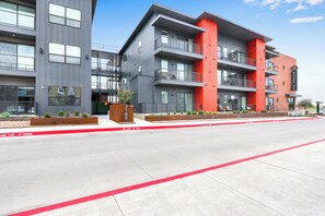 A modern multi-story building with balconies and a red accent wall. - Chic Condo Minutes to Downtown, Gruene, & More (New Braunfels)