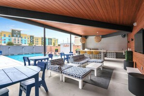 A poolside area with outdoor seating, a bar, and a view of the hotel buildings. - Chic Condo Minutes to Downtown, Gruene, & More (New Braunfels)