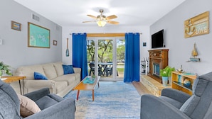A living room with a beige sofa, grey armchairs, a wooden coffee table, and a TV on a wooden stand. - Charming Lakeside Condo - Moments to Lake Fun (Canyon Lake)