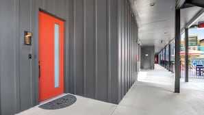 A corridor with a red door, grey walls, and a black doormat. - Pure Texas Poolside Oasis | Steps to Entertainment (New Braunfels)