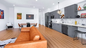 A modern kitchen with grey cabinets, a white countertop, and a hanging light fixture. - Pure Texas Poolside Oasis | Steps to Entertainment (New Braunfels)