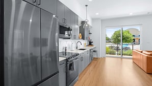 A modern kitchen with stainless steel appliances, a large window, and a view of the outdoors. - Pure Texas Poolside Oasis | Steps to Entertainment (New Braunfels)