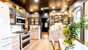 A modern kitchen with wooden flooring, white appliances, and a central island. - Best Location in Downtown NB | Golf Cart Included! (New Braunfels)