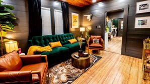 A cozy living room with a green sofa, leather armchair, and a round coffee table. - Best Location in Downtown NB | Golf Cart Included! (New Braunfels)