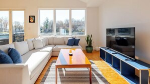 Una sala de estar moderna con un sofá modular grande, una mesa de centro de madera, un televisor y una planta en maceta.