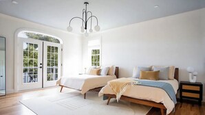 Un dormitorio amplio con dos camas, un ventanal grande y un balcón.