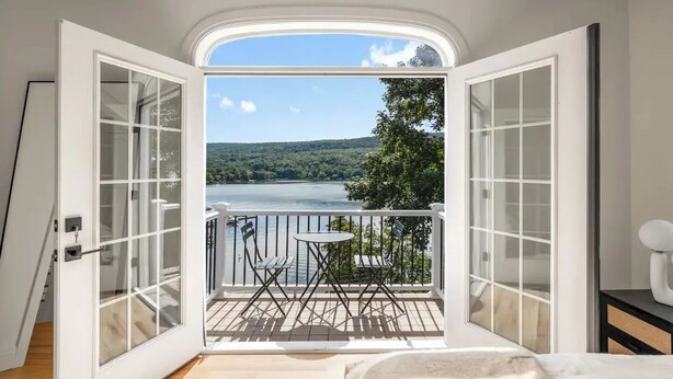 Habitación con balcón y vistas a un lago, que incluye una pequeña mesa y sillas.