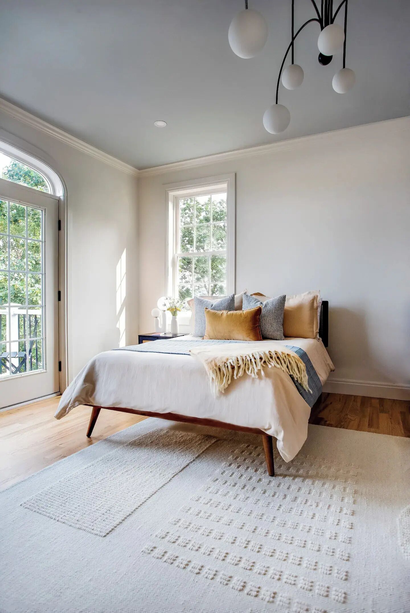 A bedroom with a bed, a window, and a ceiling light fixture.
