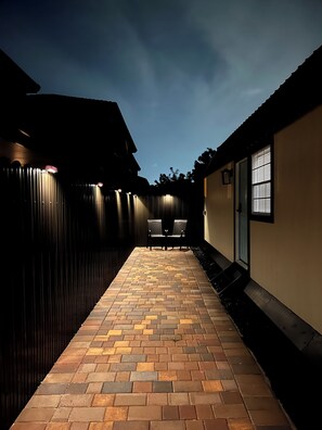 A paved patio with two chairs and a fence. - Charming Cozy Unique Tiny Home • Homestead, FL (Homestead)