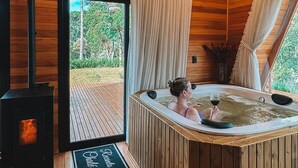 A wooden cabin interior with a hot tub, a fireplace, and a view of the outdoors. - Recanto Lavi (Urubici)