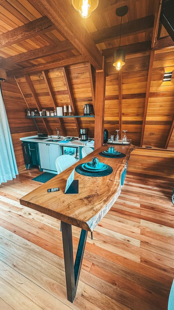 A wooden interior with a long dining table, kitchen area, and exposed wooden beams. - Recanto Lavi (Urubici)