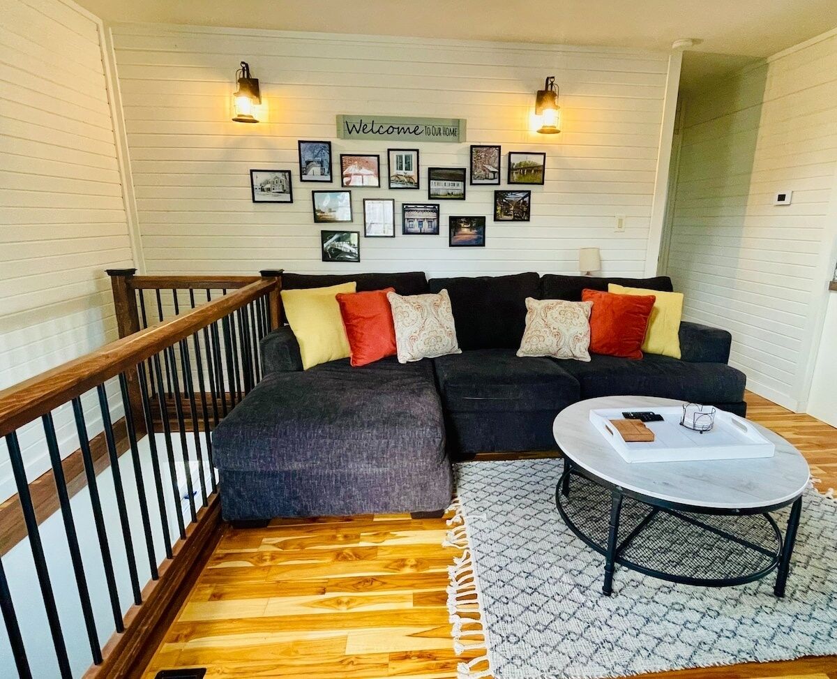 A cozy living room with a dark sofa, a wooden staircase, and a coffee table.