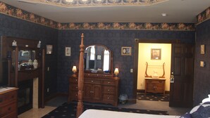 Une chambre à coucher avec un lit à baldaquin, une commode avec un miroir et une porte donnant sur une autre pièce.