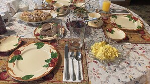 Une table à manger dressée avec des assiettes, des verres, des couverts et différents plats, ce qui indique qu’un repas va être servi.