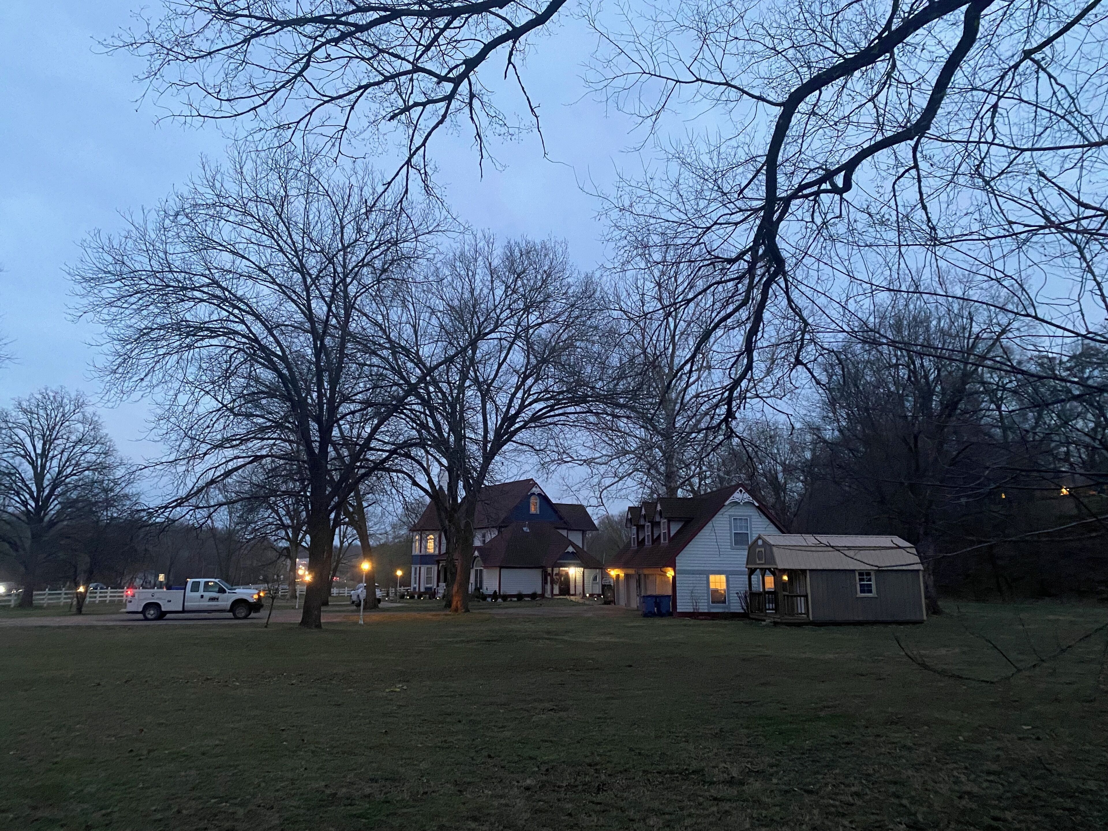 A residential area with houses, a small shed, and a white pickup truck parked on the grass.