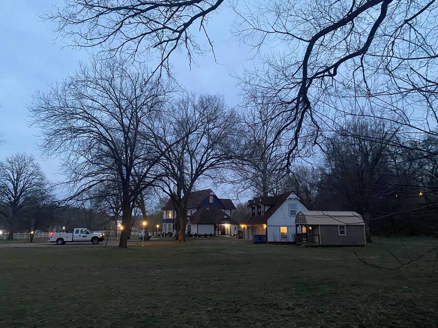 A residential area with houses, a small shed, and a white pickup truck parked on the grass.