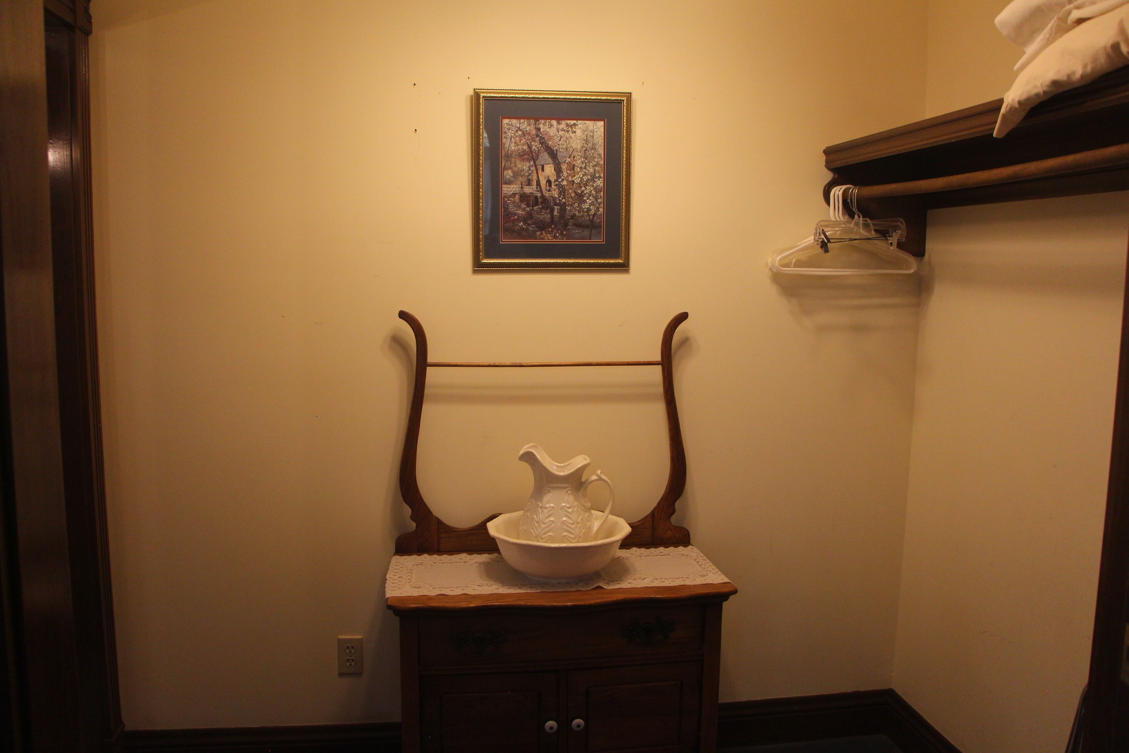 A bathroom with a wooden cabinet, a framed picture on the wall, and a towel rack.