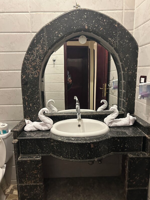 A bathroom with a marble sink, a mirror, and two swan-shaped towels. - Nile Panorama Hotel & Restaurant (Luxor)