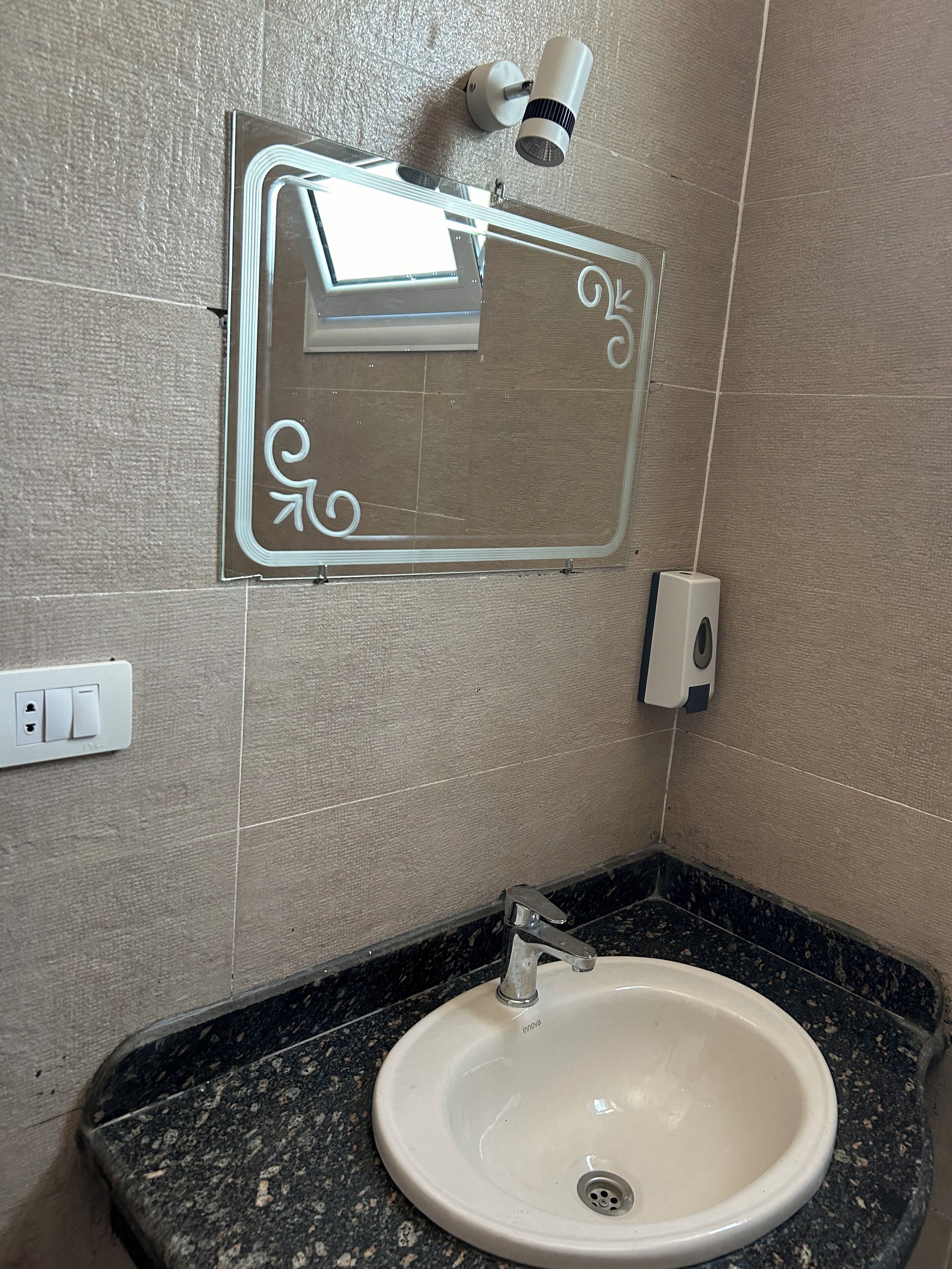 A bathroom with a white sink, a mirror, and a hand dryer.