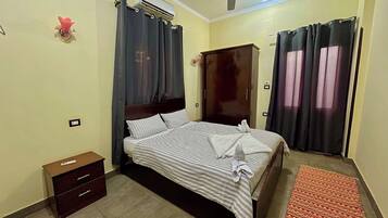 A bedroom with a bed, a wardrobe, a nightstand, and a ceiling fan.