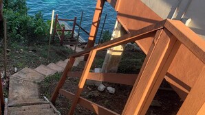 Eine Treppe führt zu einer Holzterrasse mit Blick auf ein Gewässer.